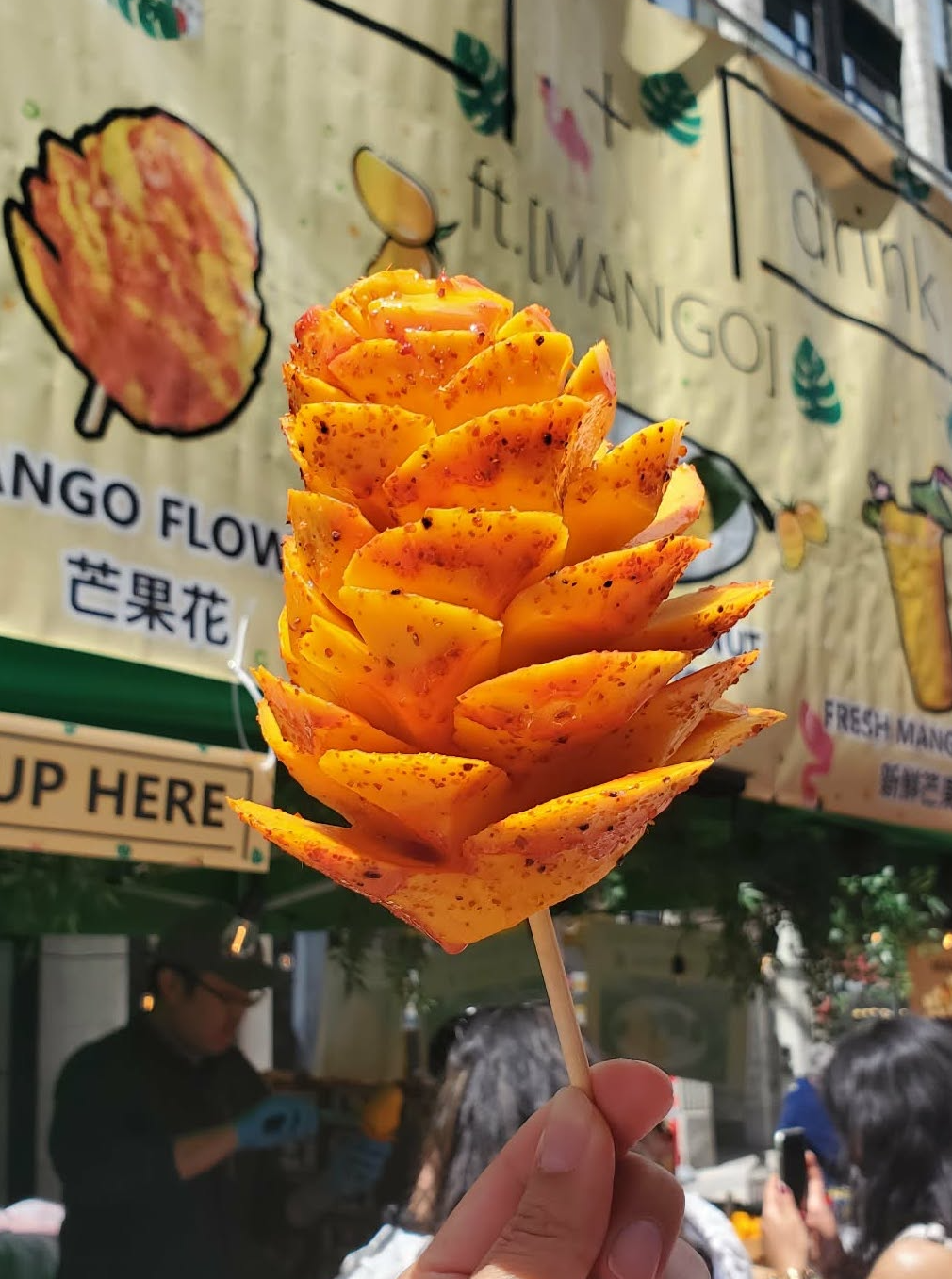 hand holding a mango with skin removed in the shape of a flower