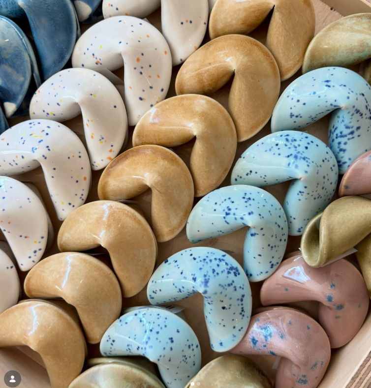 Ceramic fortune cookies lay out in perfect little rows. Vendor: Christopher He Ceramics 