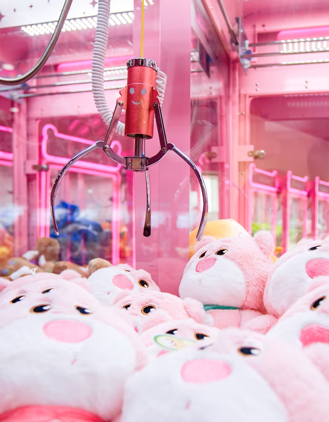 close-up view of a claw game machine reaching for adorable plushies inside. 