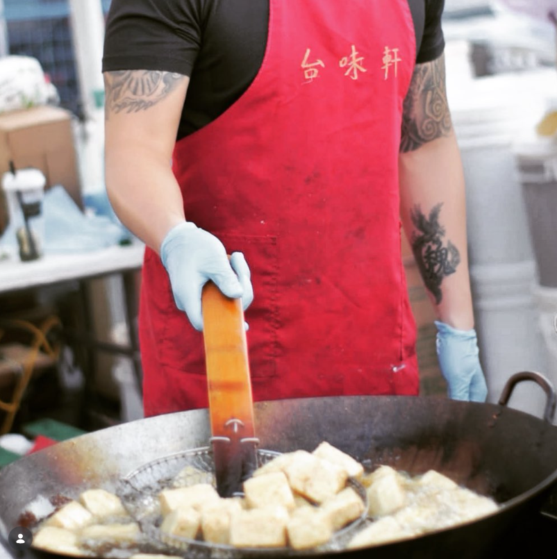 A chef cooking up fermented tofu in a giant wok over a flame. Vendor: Wei's Taiwanese Foods