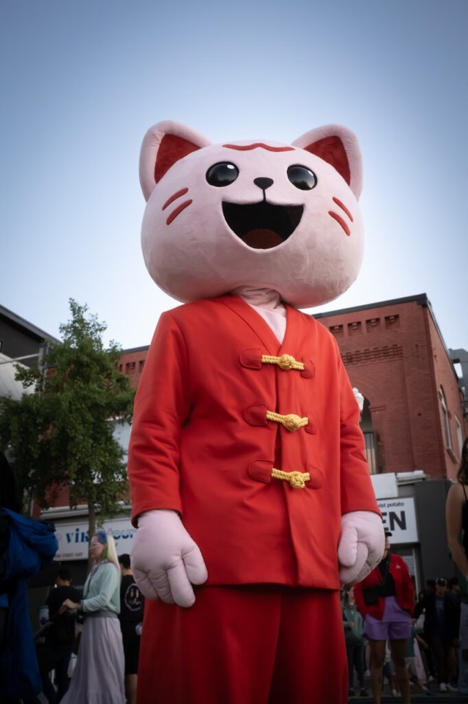 The Far East Asian Night Market Mascot, Mo. Mo is a pink cat wearing red suit.