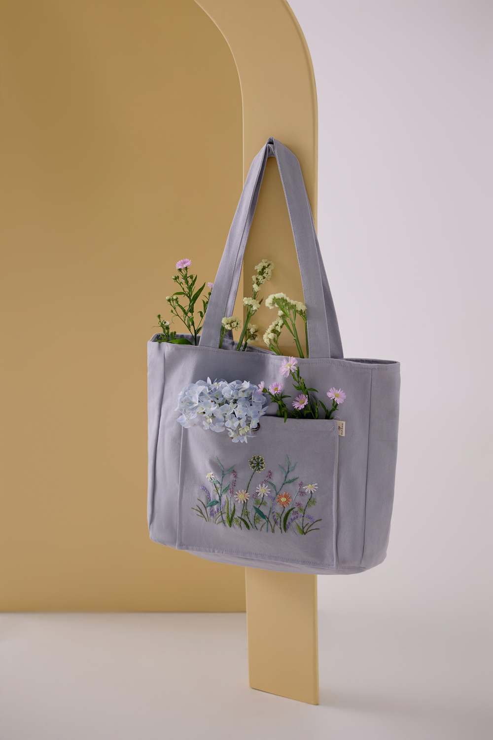 A lavender homemade satchel with embroidered colourful flowers. Vendor: Rumoon Handmade